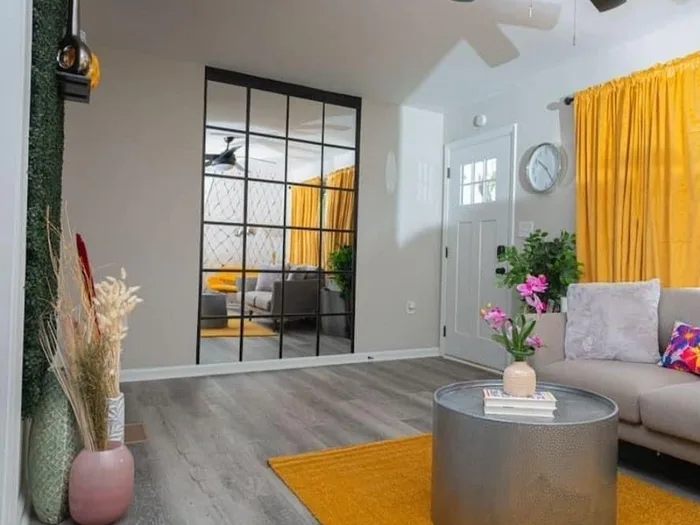 Bright living room with mirror wall and gold rug, cleaned and staged